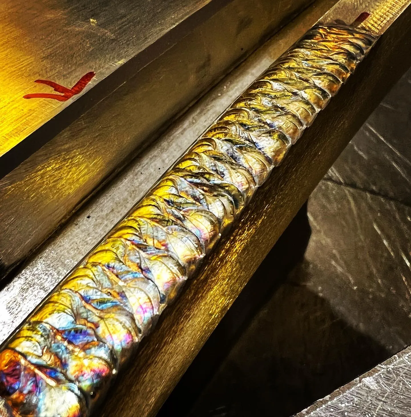 Multi-pass TIG build up weld with colorful heat tint along a metal edge