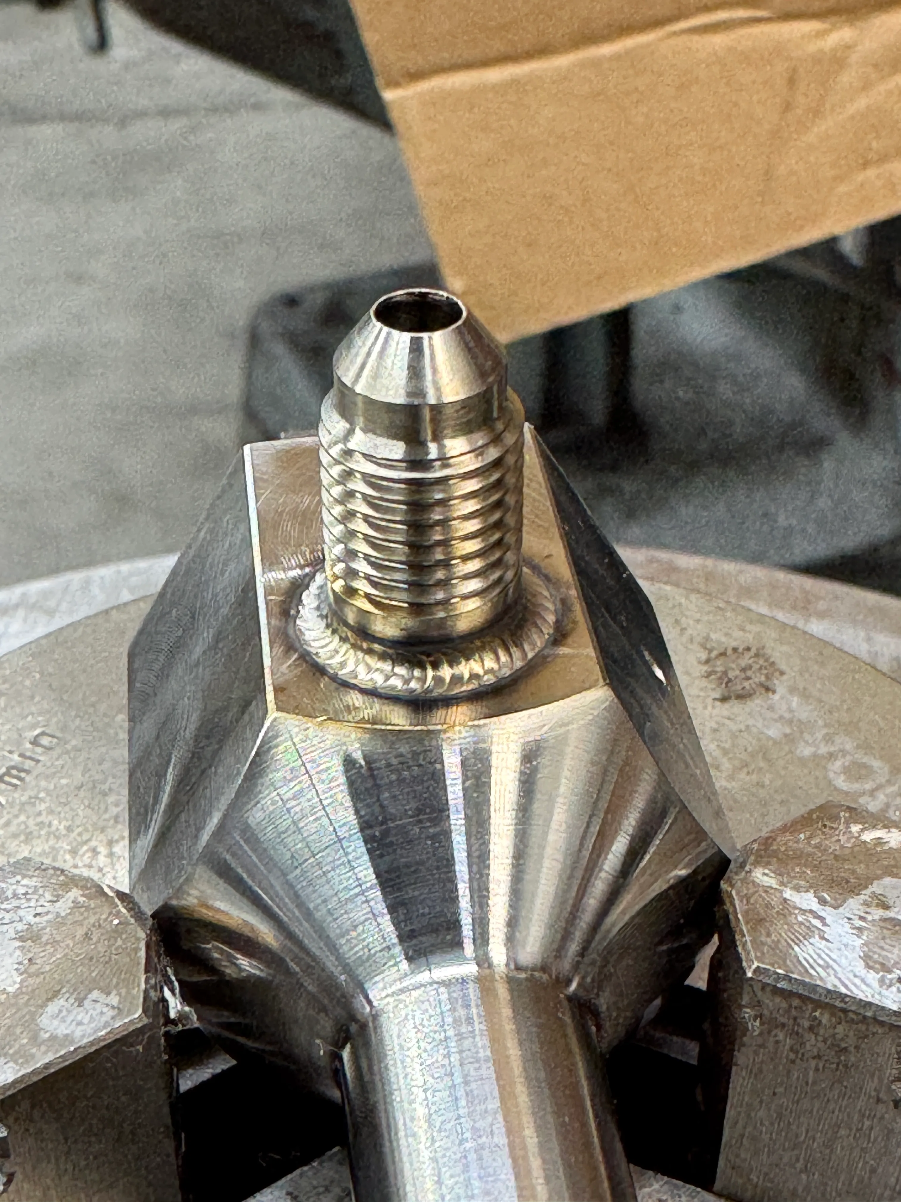 Close-up of a precise weld around a threaded metal fitting