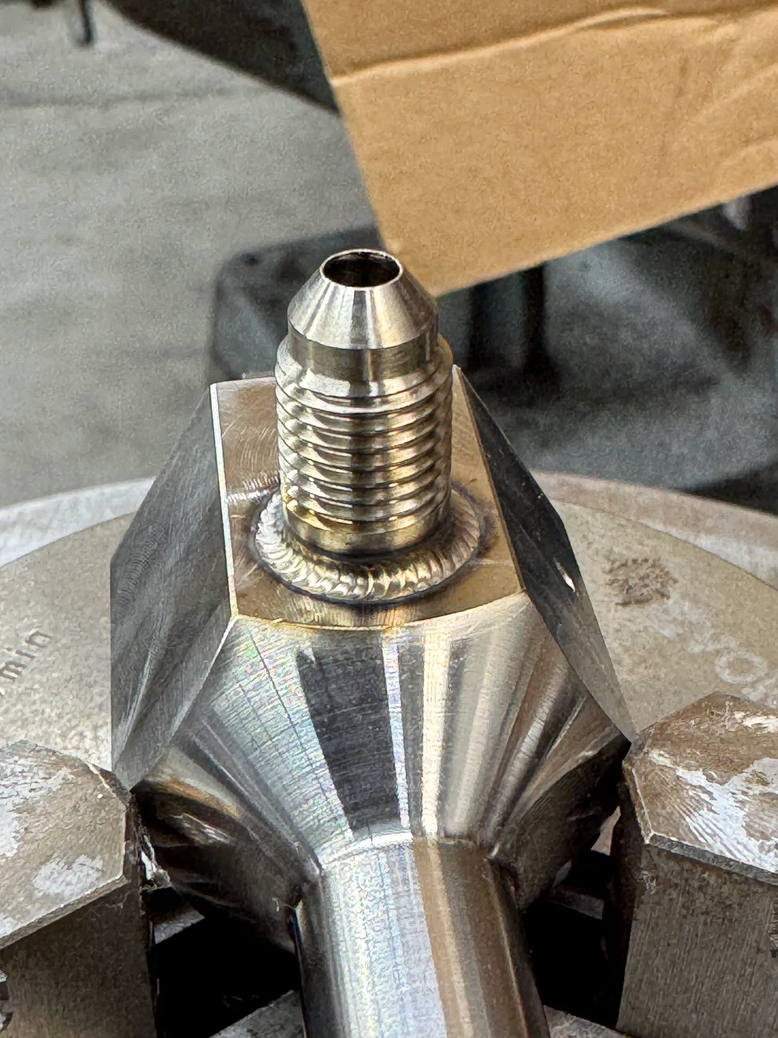 Close-up of a precise weld around a threaded metal fitting